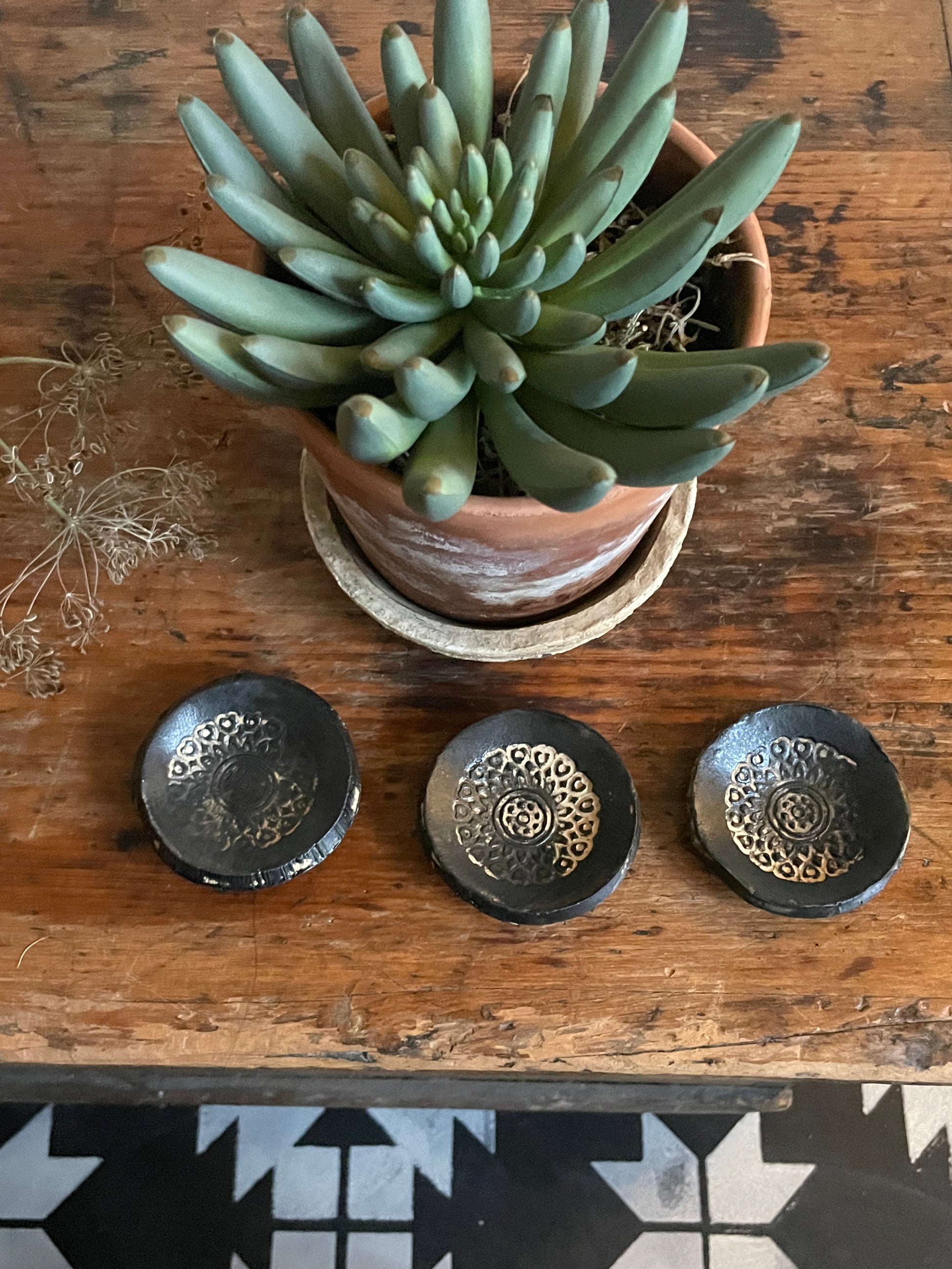 Three tiny trinket dishes in a black matte finish with a boho texture lined up.