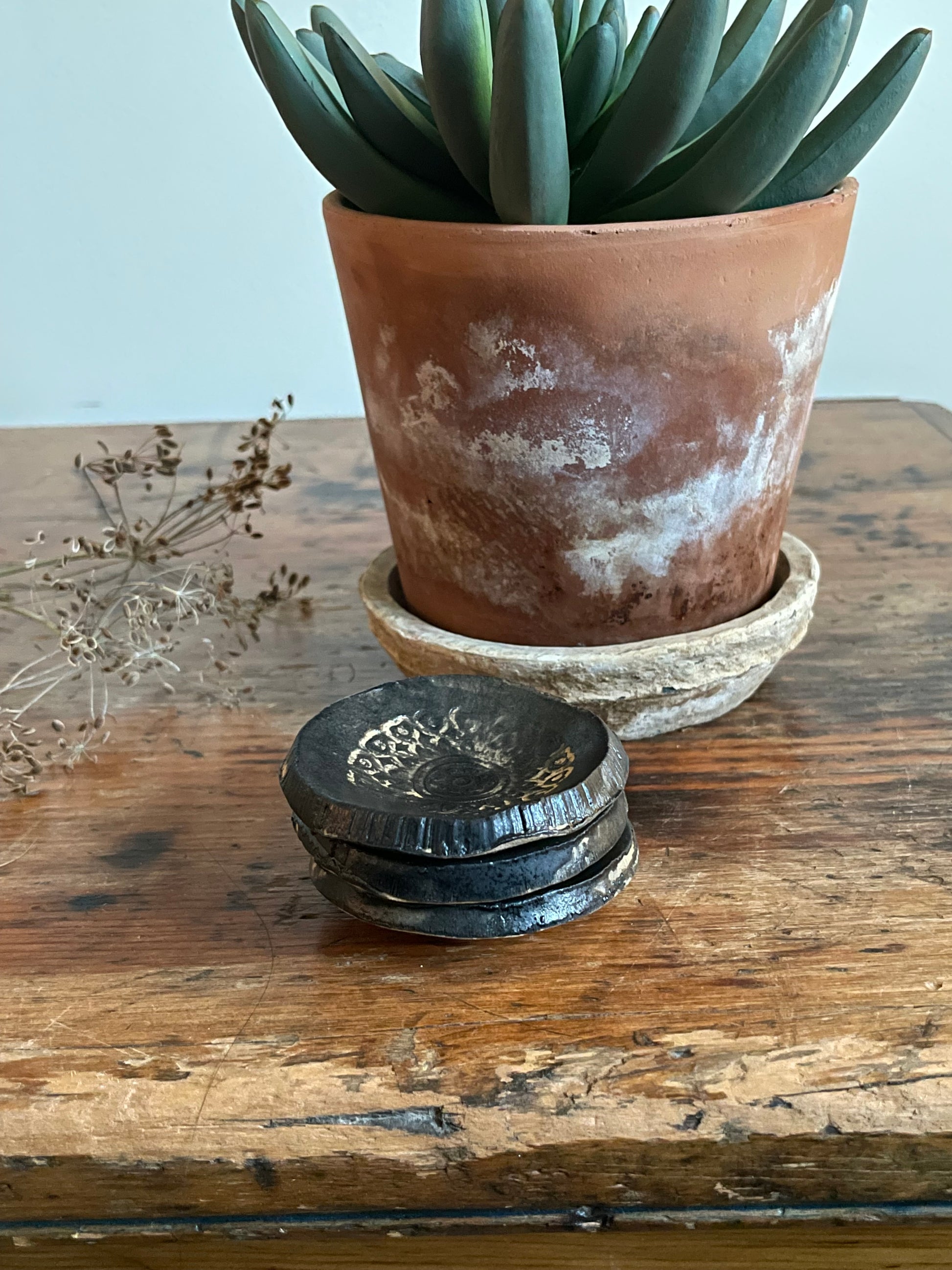 Stack of three tiny dishes in black matte with texture in white.