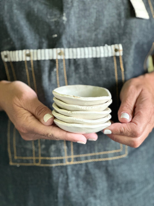 Stack of someone holding handmade tiny matte white bowls.